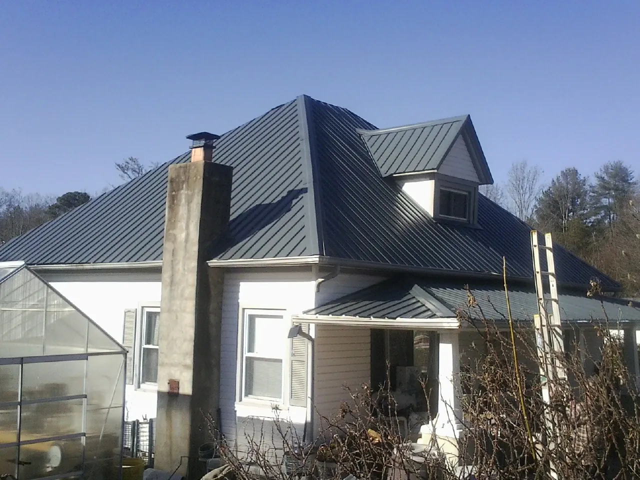 Dark blue standing seam metal roof on a white farmhouse with dormer — Slate & Tile Roof Repair by Roofing Brothers in Rocklin