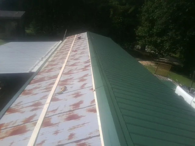 Old rusted panels beside newly installed green metal roofing — Wind Damage Roof Repair by Roofing Brothers in Rocklin