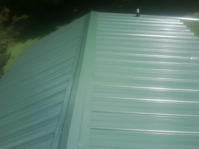 New green metal panels meeting at the ridge of a roof — Flat Roof Repair work by our crew in Rocklin