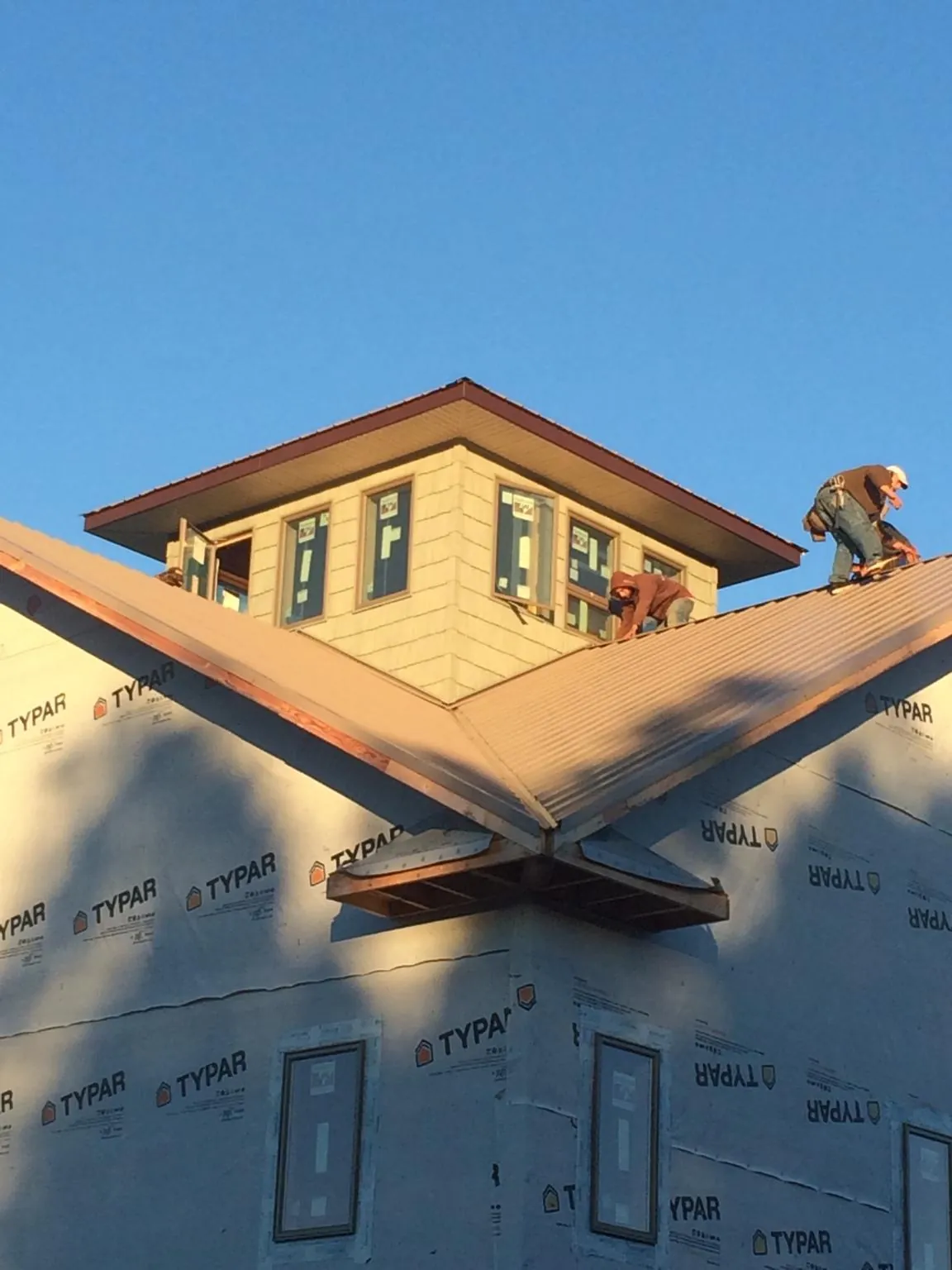 Roofers working around a rooftop cupola on a new metal roof at sunset — Roof Waterproofing in Rocklin by Roofing Brothers